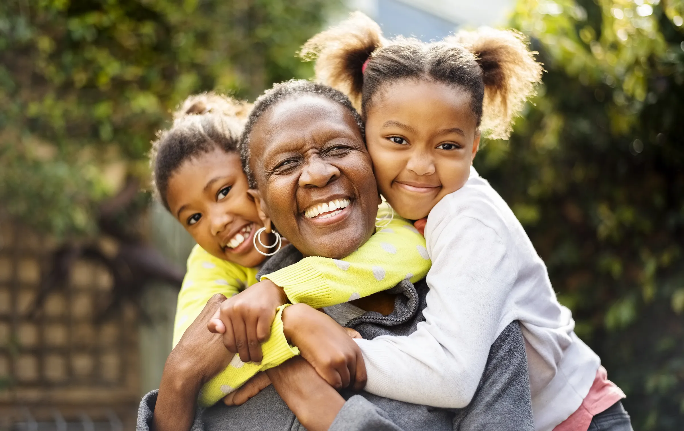 Grandmother smiling with two grandchildren in a garden