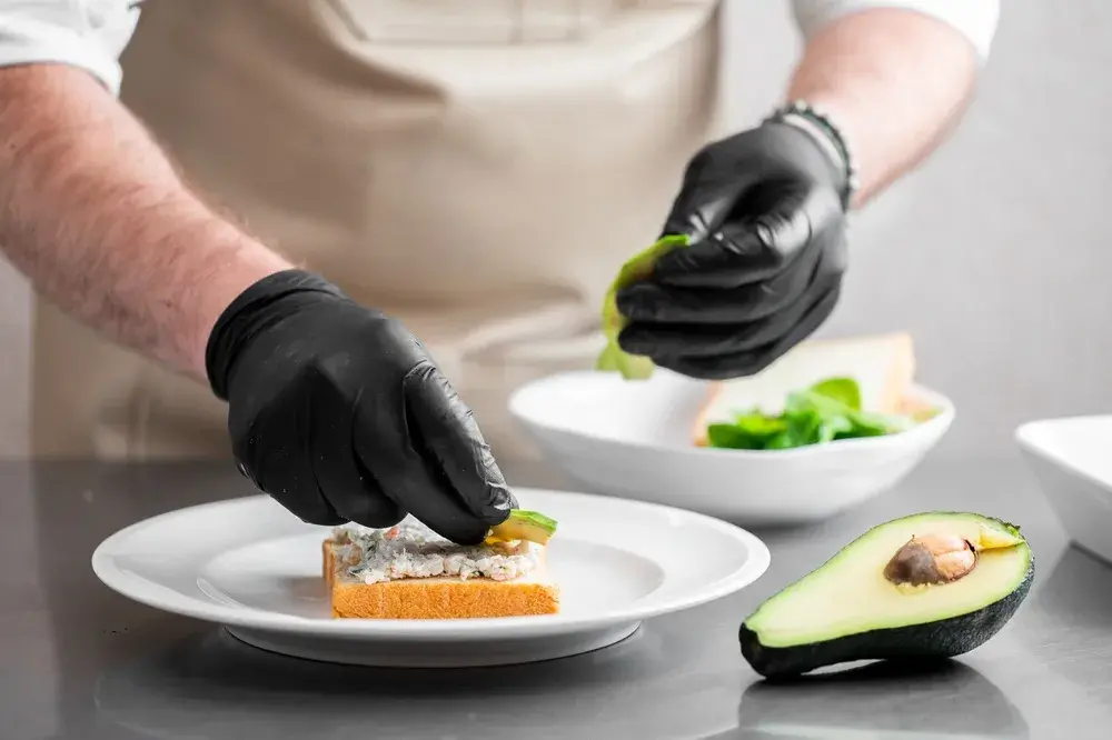 Chef garnishing avocado toast with greens on a plate